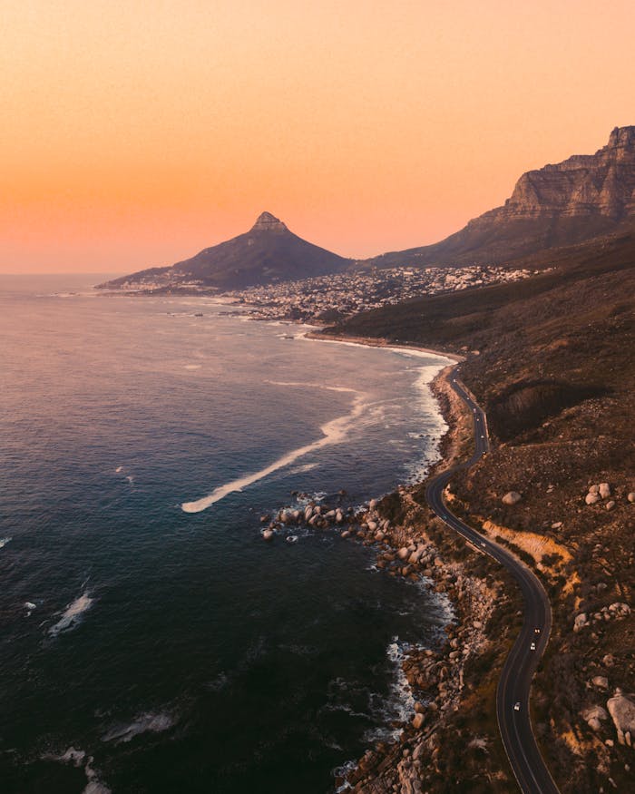 A breathtaking view of Cape Town's coastal road and Lion's Head at sunset, capturing the vibrant hues of the sky.