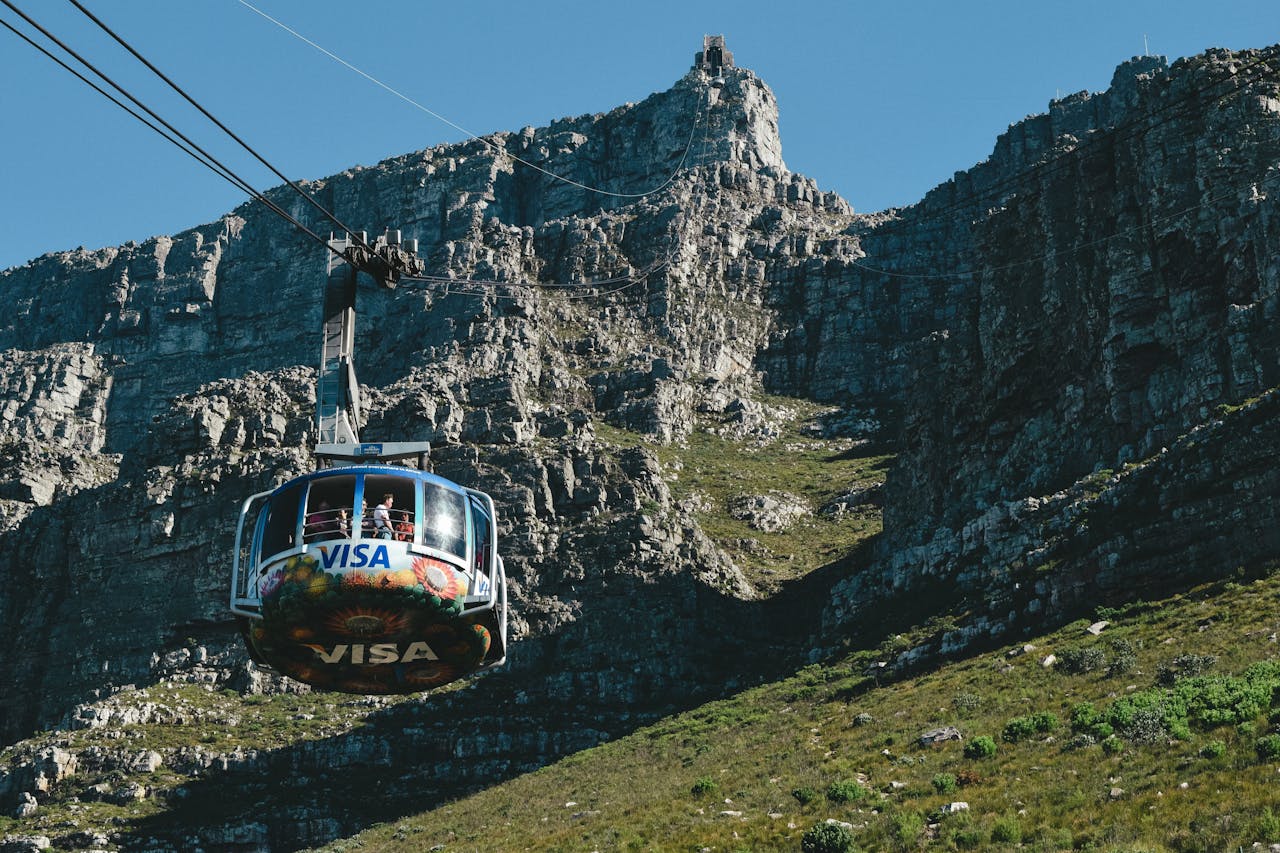 A cable car ascends a rocky mountain, offering panoramic views and adventure.
